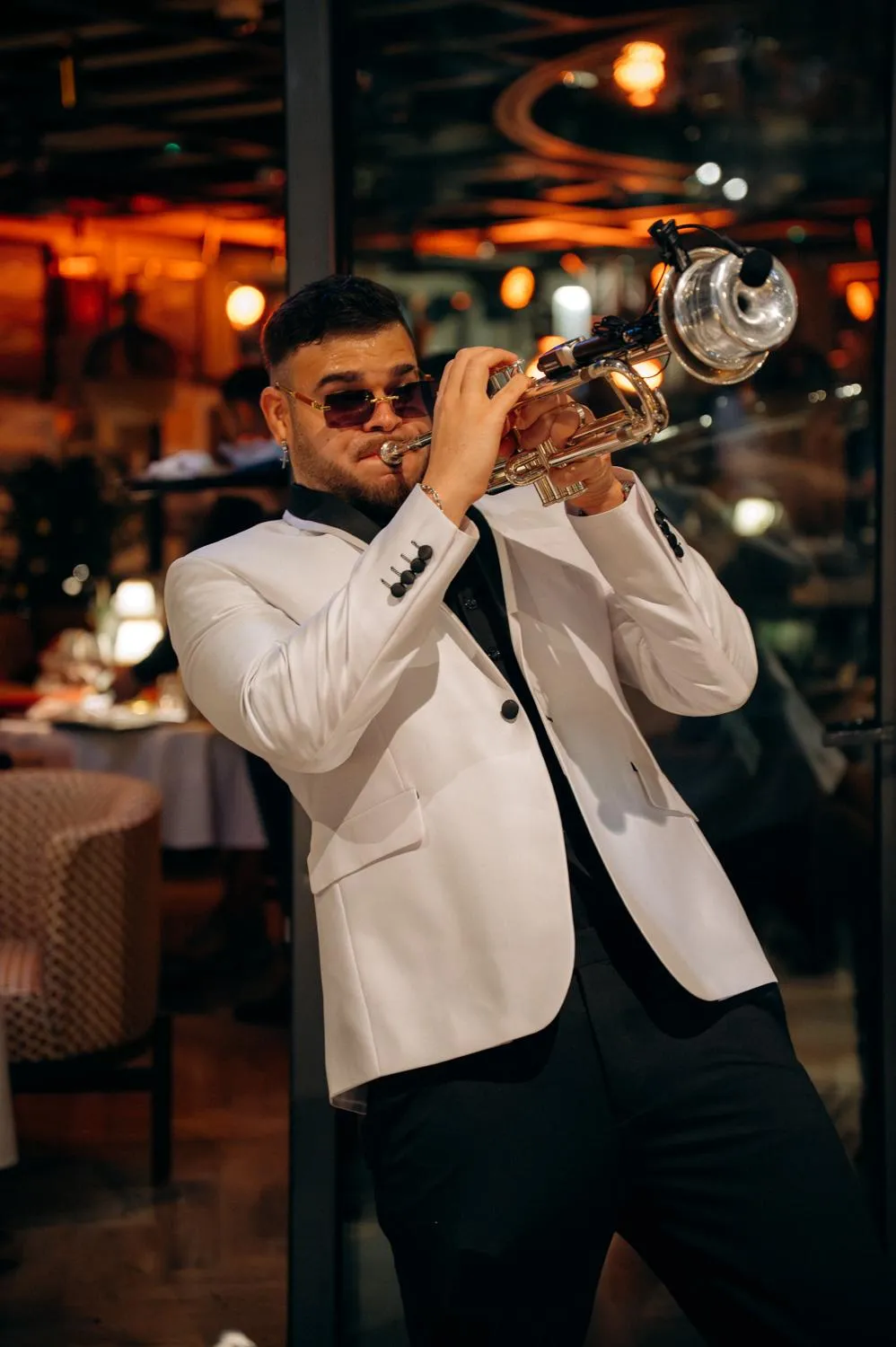 Darien Polo performing live with trumpet in a white tuxedo